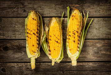 Grilled corn cobs on vintage wood background - obrazy, fototapety, plakaty