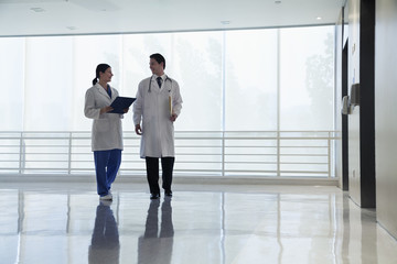 Fototapeta premium Two doctors walking and smiling in the hospital, full length