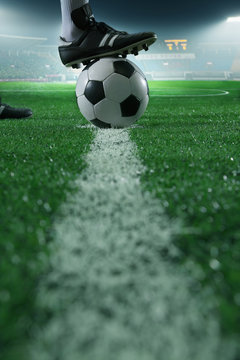 Close up of foot on top of soccer ball on the line, side view, stadium