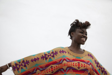 Portrait of young smiling woman holding her arms out in traditional clothing from Africa, studio shot