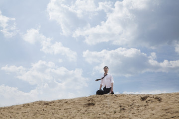 Obraz premium Young businessman lost and walking through the desert, distant 
