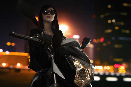 Beautiful Young Woman In Sunglasses Sitting On A Motorcycle At Night Time In Beijing