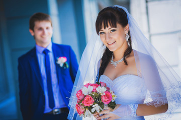 happy newlyweds against a blue modern building