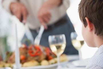 Little boy looking at a man carving the roast chicken