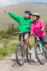 Obraz premium Athletic couple on a bike ride wearing hooded jumpers with man p