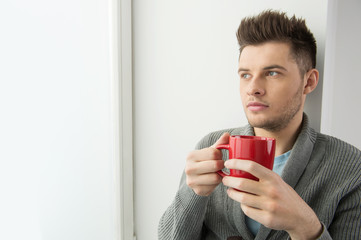 Men drinking coffee. Cheerful young men holding red cup and look