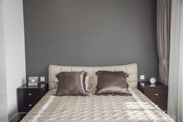 Bright, modern bedroom with beige bedspread. 