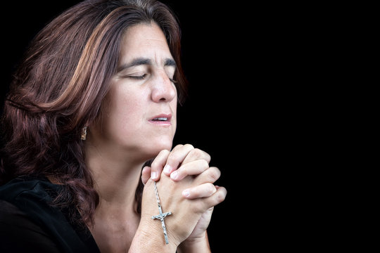 Portrait of an hispanic woman praying isolated on black