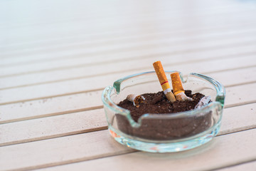 Ashtray with lit cigarette on a wooden table