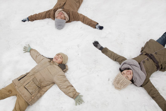 Family laying in snow making snow angels