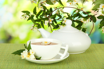 Cup of tea with jasmine, on bamboo mat, on bright background