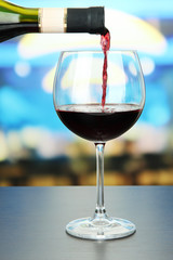 Red wine being poured into wine glass, on bright background