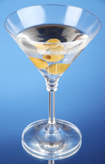 Martini with green olives on blue background