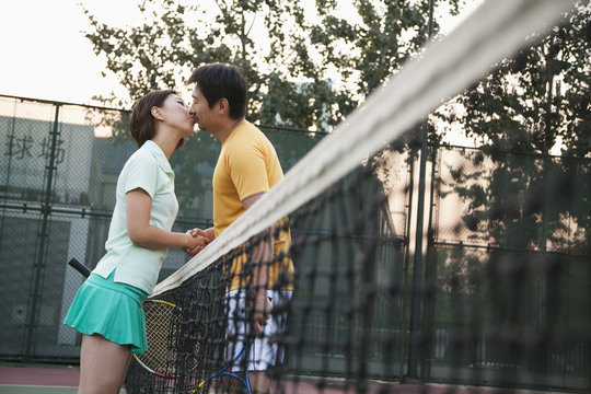 Couple kissing over the tennis net