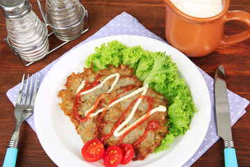 Potato pancakes on plate, on wooden background