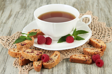 Cup of tea with cookies and raspberries on table close-up
