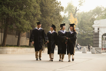 Young Graduates Walking Across Campus