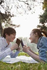 Teenage couple reading books in the park 