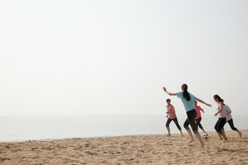 Young Friends Playing Soccer on the Beach