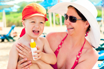 Mom and son on the beach to protect the skin from sun lotion