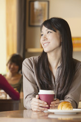 Beautiful young woman sitting at a coffee shop, looking away