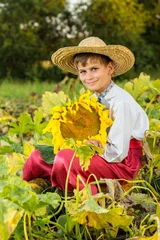 Foto op Canvas Young happy boy hold sunflower in a garden © Sergii Figurnyi