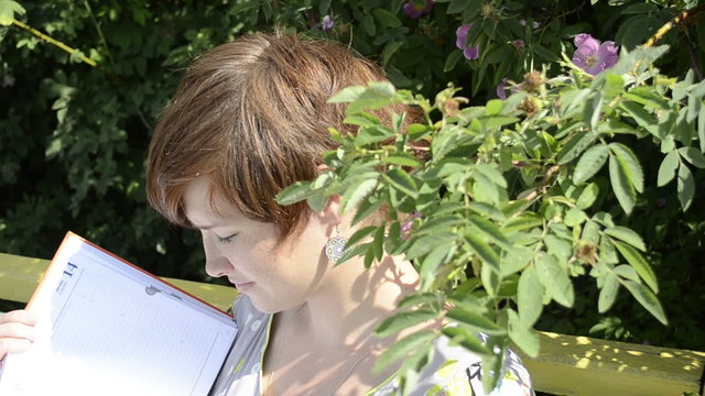 Pregnant woman reading magazine on the bench
