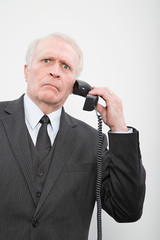 Naklejka premium A confused businessman using a telephone