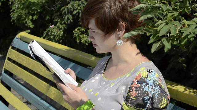Pregnant woman reading magazine on the bench