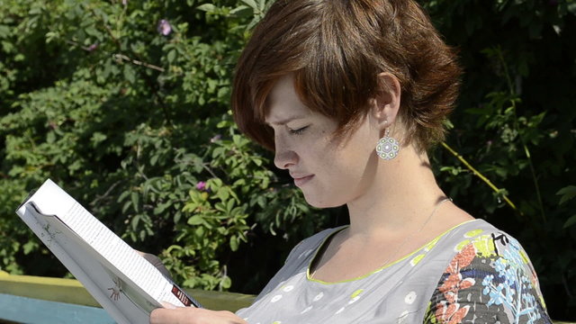 Pregnant woman reading magazine in summer day