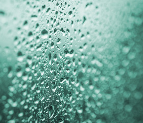 Drops on a glass with selective focus. Emerald toned image.