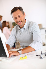 Cheerful man sitting in office and working on desktop