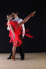 Latino dancers in ballroom against black background