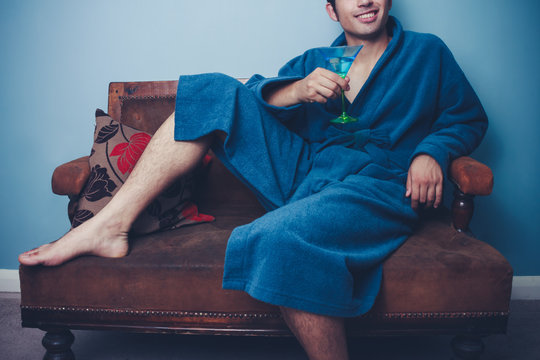 Happy young man in dressing gown drinking cocktails