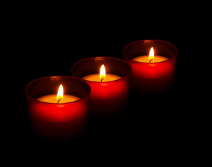 Red votive candles burning in the dark, black background