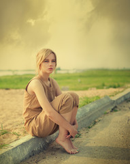 beautiful girl sitting on the edge of the road