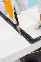 Worker cutting an insulation panel with a scale model knife