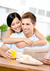 Obraz na płótnie Canvas Woman embraces eating boyfriend who sits at the kitchen