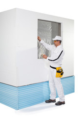 Worker taping a frame of window with a masking tape