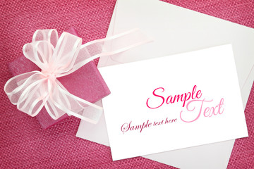 Gift box with ribbon and white invitation card