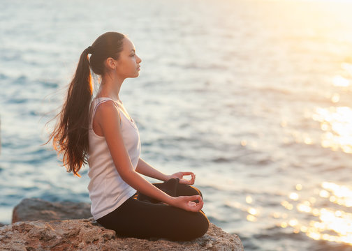 girl in lotus pose at sunset