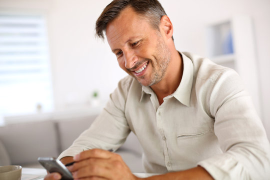 Smiling guy sending message with smartphone