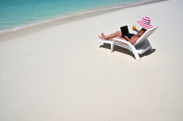 Fototapeta na wymiar Girl with a laptop on the tropical beach. Exuma, Bahamas