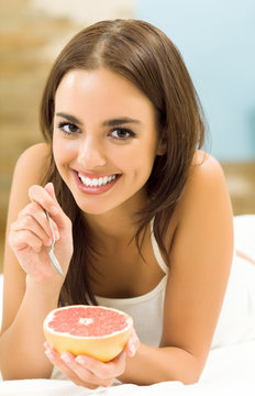 Portarit of woman eating grapefruit at home