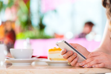 Young woman in ice cream parlor with phone texting