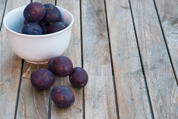 Arrangement of damson plums on wooden boards