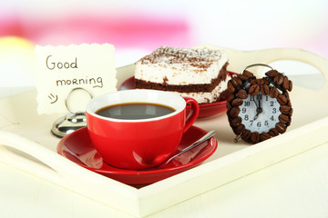 Cup of tea with cakes on wooden tray on table in room