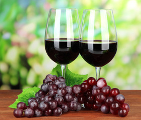 Fototapeta na wymiar Ripe grapes and glasses of wine, on bright background