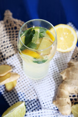 Glass of cold tea with ginger on napkin on blue table