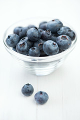 Glass dish with freshly picked blueberries, vertical shot
